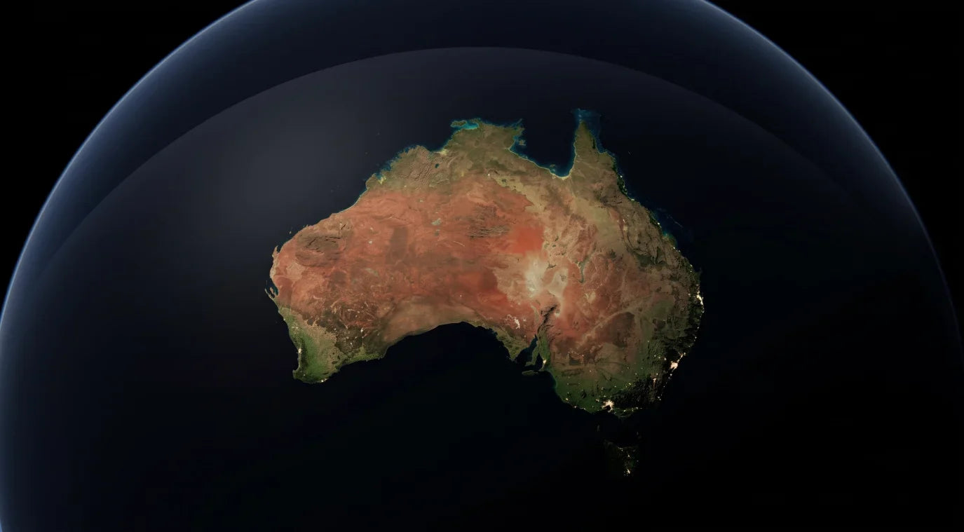 "Satellite view of Australia illuminated on a dark globe against a black background, showing red desert interior, coastal terrain, and city lights along the coastline representing the origin country of Retaliate the home of icedout gshocks.